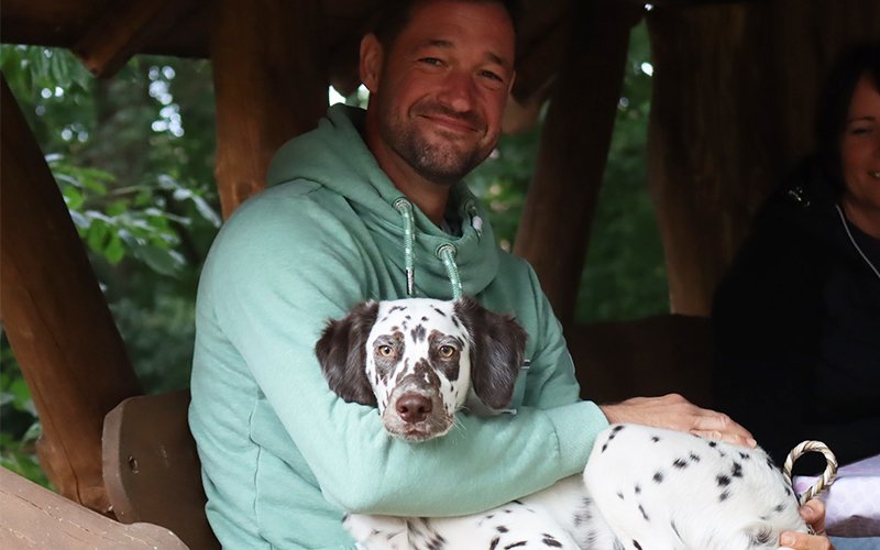 Langhaar Dalmatiner Welpen auf dem Arm eines Mannes