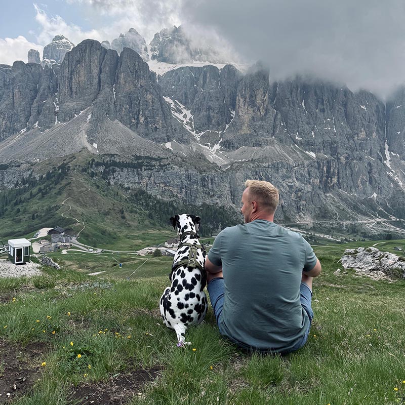 ein Mann mit einem Dalmatiner auf den Bergen wandern. Sitzen auf einer Wiese